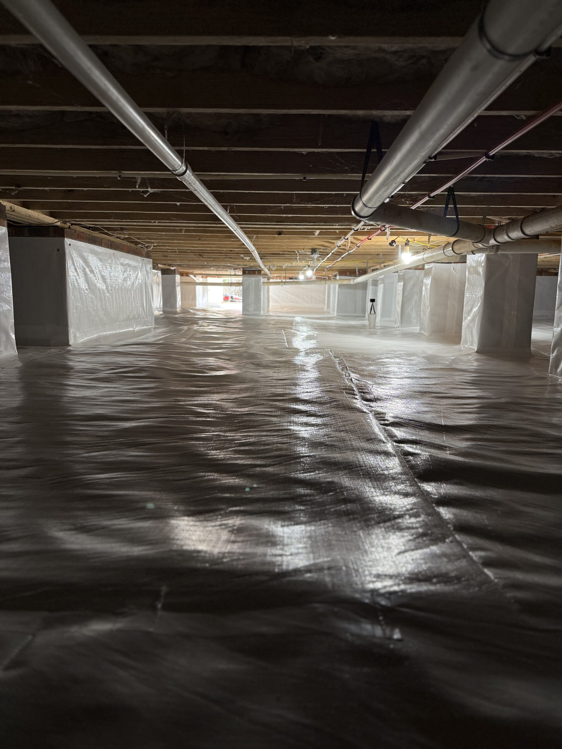 Waterproofing specialist inspecting basement wall seepage with moisture meter and protective equipment