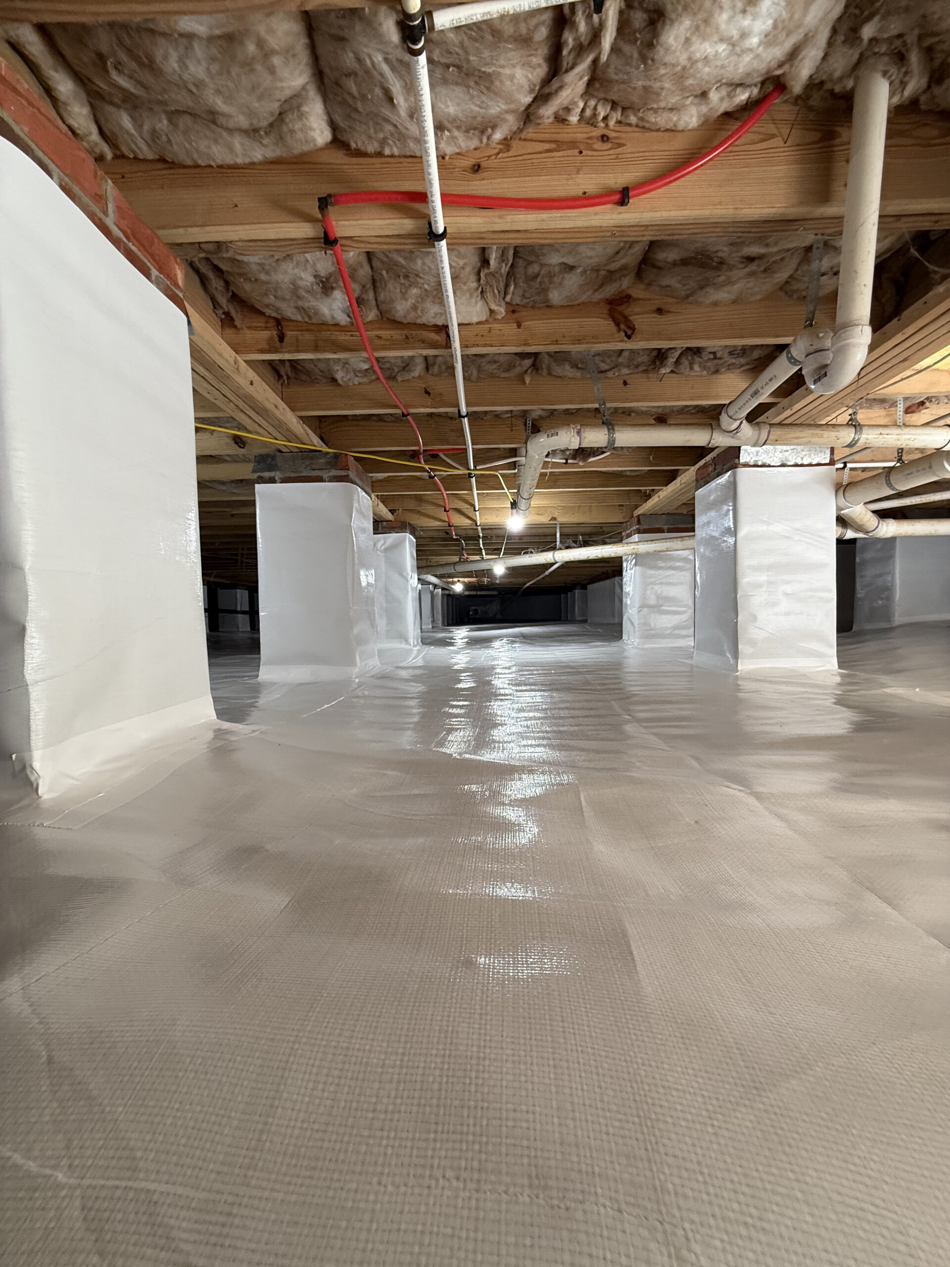 Waterproofing specialist inspecting basement wall seepage with moisture meter and protective equipment